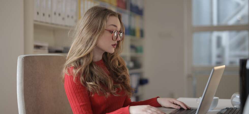 woman in red long sleeve shirt wearing eyeglasses using a laptop